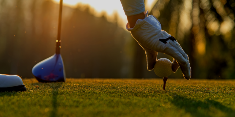 golfer puts golf ball on tee