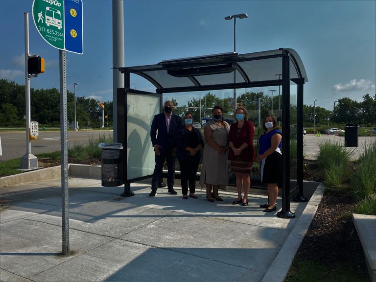 Five People posing at a new bus stop on route 10 and 37